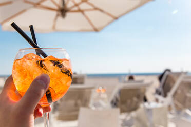 Close-Up Of Hand Holding Drink At Beach - EYF06378