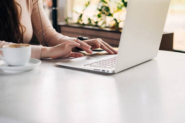 Midsection der Frau mit Laptop auf dem Tisch - EYF06425