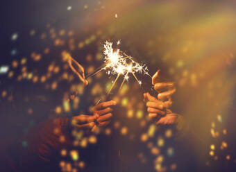 Cropped Hands Of People Holding Sparkler At Night - EYF06427