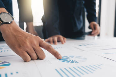 Mittelteil von Geschäftsleuten, die Diagramme auf dem Schreibtisch im Büro analysieren - EYF06490