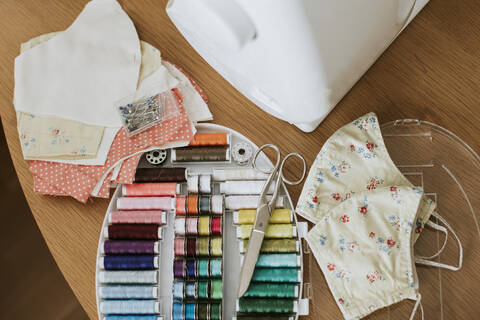 Floral face masks with sewing items on table at home during COVID-19 stock photo