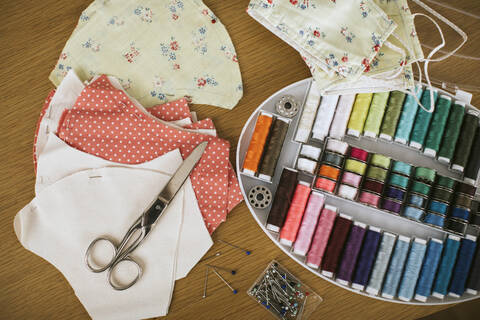 Close-up of sewing items with floral protective masks on table at home stock photo