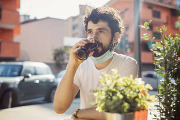 Nahaufnahme eines jungen Mannes, der in einem Straßencafé sitzt und einen Saft trinkt - MEUF00914