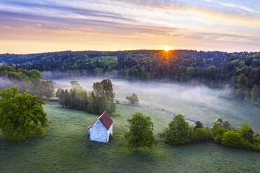 Germany, Bavaria, Egling, Drone view of Kapelle Saint Koloman at foggy springtime sunrise - SIEF09900