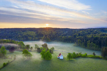 Deutschland, Bayern, Egling, Drohnenansicht der Kapelle St. Koloman bei nebligem Frühlings-Sonnenaufgang - SIEF09901