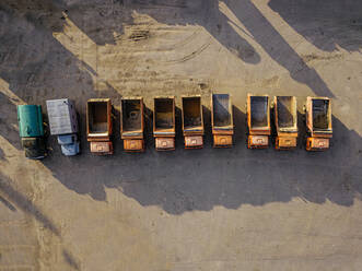 Luftaufnahme einer Reihe alter leerer Lastwagen, die nebeneinander geparkt sind - KNTF04683