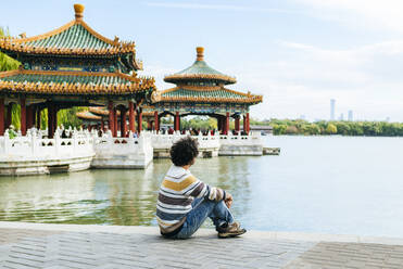 Mann sitzt auf einem Fußweg am See im Beihai-Park, Peking, China - KIJF03087