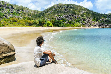 Man sitting on rock at Magnetic island, Queensland, Australia - KIJF03093