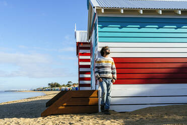 Man standing by cottage at Brighton Beach, Melbourne, Australia - KIJF03104