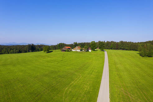 Deutschland, Bayern, Reit im Winkl, Drone view of dirt road leading to small countryside village in spring - SIEF09927