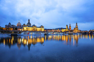 Germany, Saxony, Dresden, Tourboats moored along bank of Elbe at dusk with city skyline in background - PUF01903