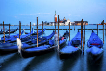 Italien, Venetien, Venedig, Gondeln im Yachthafen in der Abenddämmerung mit San Giorgio Maggiore im Hintergrund - PUF01910