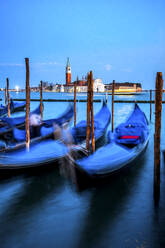 Italy, Veneto, Venice, Gondolas moored in marina at dusk with San Giorgio Maggiore in background - PUF01911