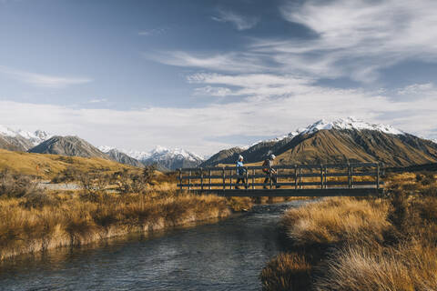 Couple of young hikers crossing a creek, Lake Clearwater, New Zealand stock photo