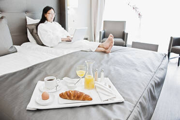 Geschäftsfrau beim Frühstück im Bett in einem luxuriösen Business-Hotel - CAVF85503