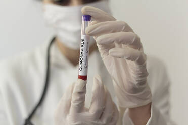 Midsection Of Scientist Holding Test Tube Wearing Flu Mask On Table - EYF06535