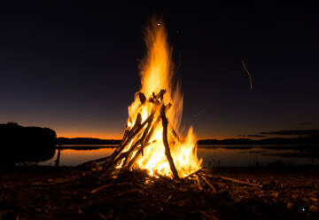 Lagerfeuer am Strand gegen den Himmel bei Nacht - EYF06542