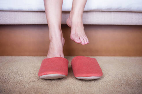 Low Section Of Woman Removing Slippers By Bed - EYF06576