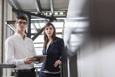 Business people looking away while standing in factory - DIGF12699