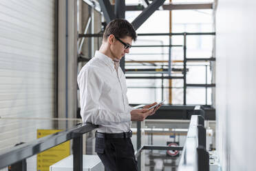 Businessman using digital tablet while standing in factory - DIGF12701