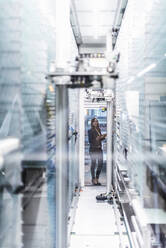 Businesswoman examining production in factory seen through glass - DIGF12707