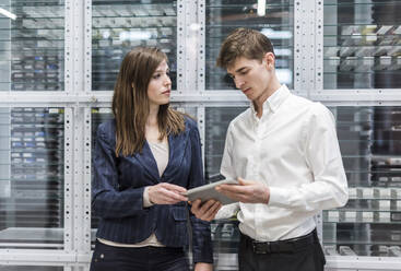 Professionelle Mitarbeiter diskutieren über ein digitales Tablet, während sie in einer Fabrik stehen - DIGF12711