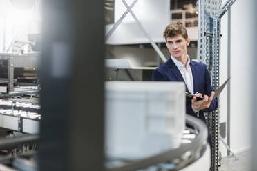 Male manager holding file examining production line in factory - DIGF12723