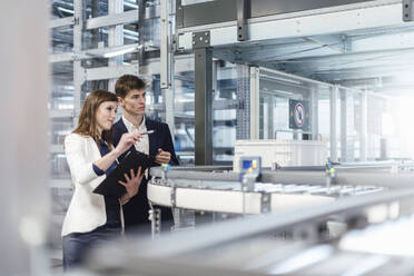 Business professionals examining production line in factory - DIGF12726