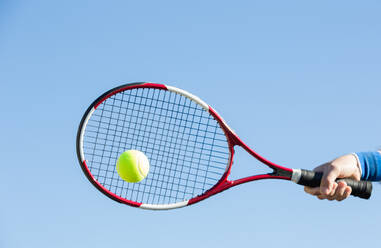 Abgeschnittene Hand beim Tennisspielen gegen den klaren Himmel - EYF06623