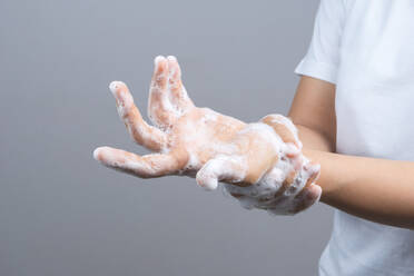 Close-Up Midsection Of Woman Washing Hands Over Gray Background - EYF06714