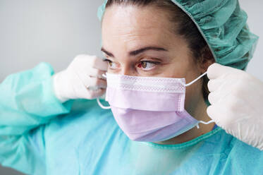 Nahaufnahme einer Krankenschwester mit chirurgischer Maske, die in einer Klinik wegschaut - JCMF00874