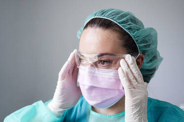 Nahaufnahme einer Krankenschwester mit Schutzbrille, die in einer Klinik wegschaut - JCMF00876