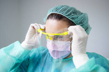 Close-up of nurse wearing face shied against wall in clinic - JCMF00877