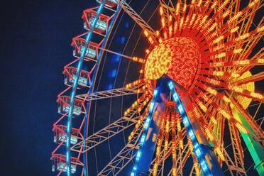 Low Angle View of Illuminated Ferris Wheel gegen den Himmel bei Nacht - EYF06793