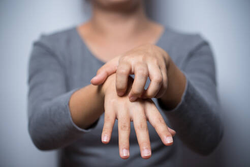 Midsection of Woman Scratching Hand gegen grauen Hintergrund - EYF06837