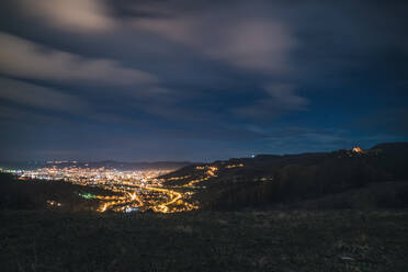 Beleuchtete Stadtlandschaft gegen den Himmel bei Nacht - EYF06845