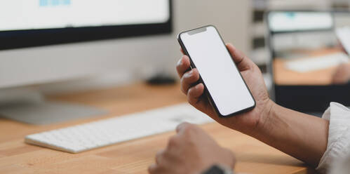 Cropped Hände von Geschäftsmann mit leeren Telefon am Schreibtisch - EYF06848