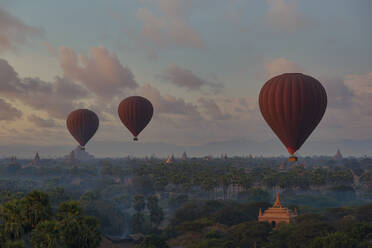 Myanmar, Region Mandalay, Bagan, Heißluftballons fliegen in der Morgendämmerung über buddhistischen Tempeln - TOVF00196