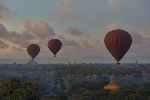 Myanmar, Region Mandalay, Bagan, Heißluftballons fliegen in der Morgendämmerung über buddhistischen Tempeln - TOVF00196
