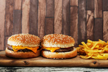 Nahaufnahme von Hamburgern und Pommes frites auf Holztablett - EYF06894