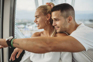 Young couple looking through window while sitting in Ferris wheel - MIMFF00060