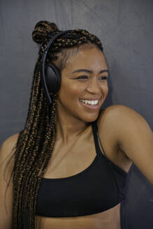 Close-up of smiling female athlete listening music through headphones in gym - VEGF02369