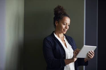 Portrait of businesswoman using digital tablet in office - RBF07716