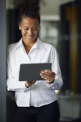 Porträt einer lächelnden Geschäftsfrau, die ein digitales Tablet im Büro benutzt - RBF07719