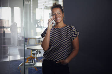 Porträt einer lächelnden Geschäftsfrau am Telefon in einem modernen Büro - RBF07727