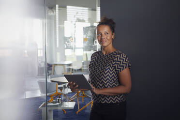 Porträt einer lächelnden Geschäftsfrau mit digitalem Tablet in einem modernen Büro - RBF07732