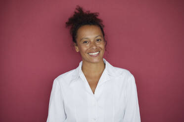 Porträt einer lächelnden Geschäftsfrau vor rotem Hintergrund - RBF07735