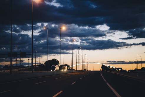 Spanien, Provinz Barcelona, Barcelona, Dunkle Gewitterwolken über der Stadtautobahn in der Abenddämmerung - OCMF01363