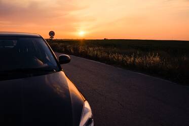 Cropped Image of Car On Road By Field Against Sky During Sunrise - EYF06918