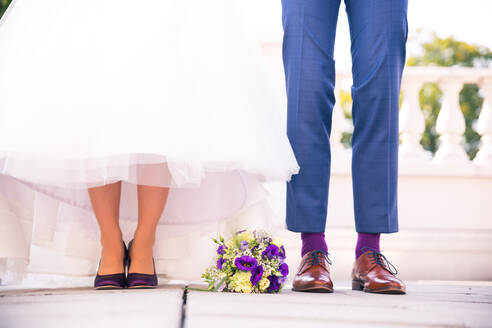 Niedriger Ausschnitt von Braut und Bräutigam mit Blumenstrauß auf dem Boden stehend - EYF06951